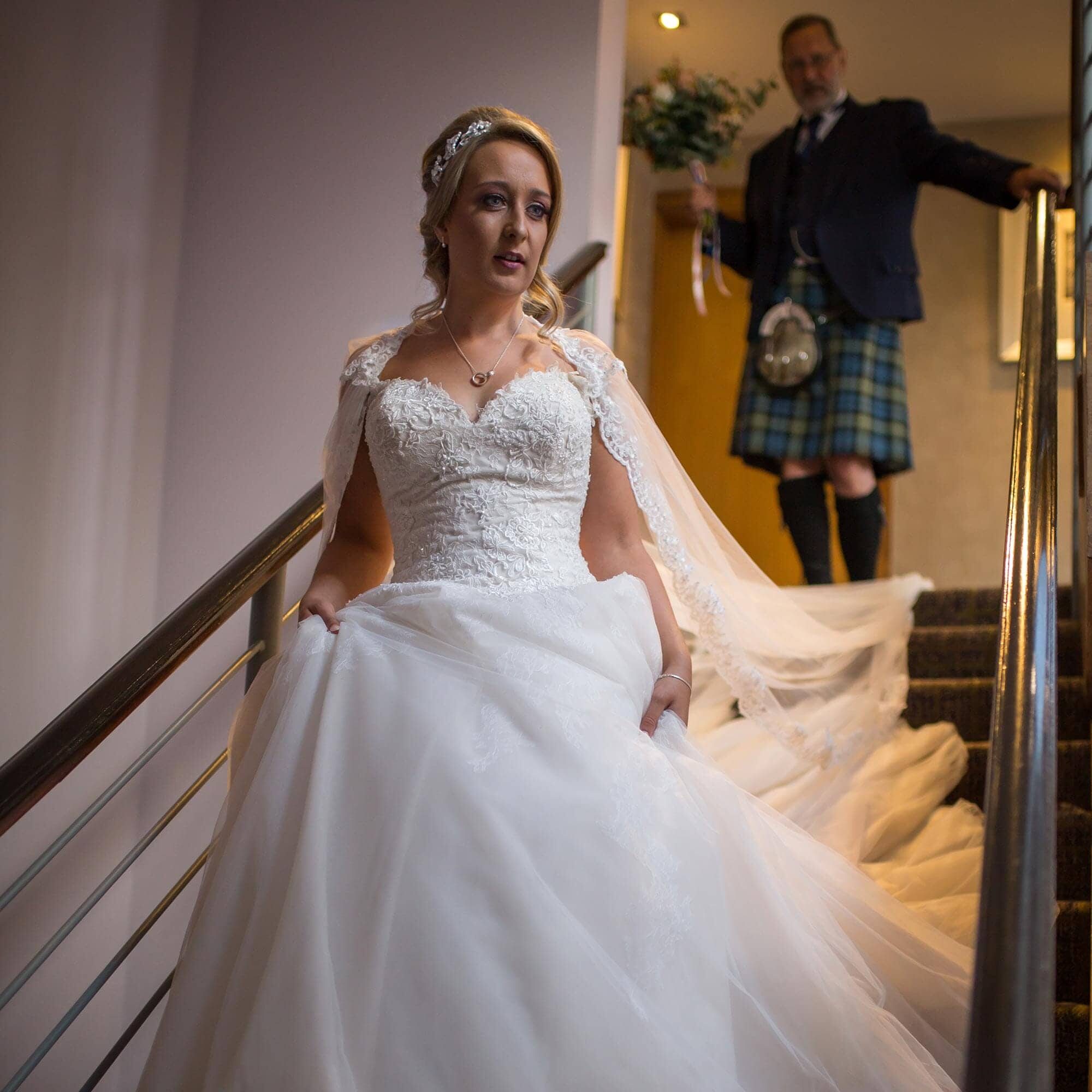 Bride walking down stairs with dad behind her